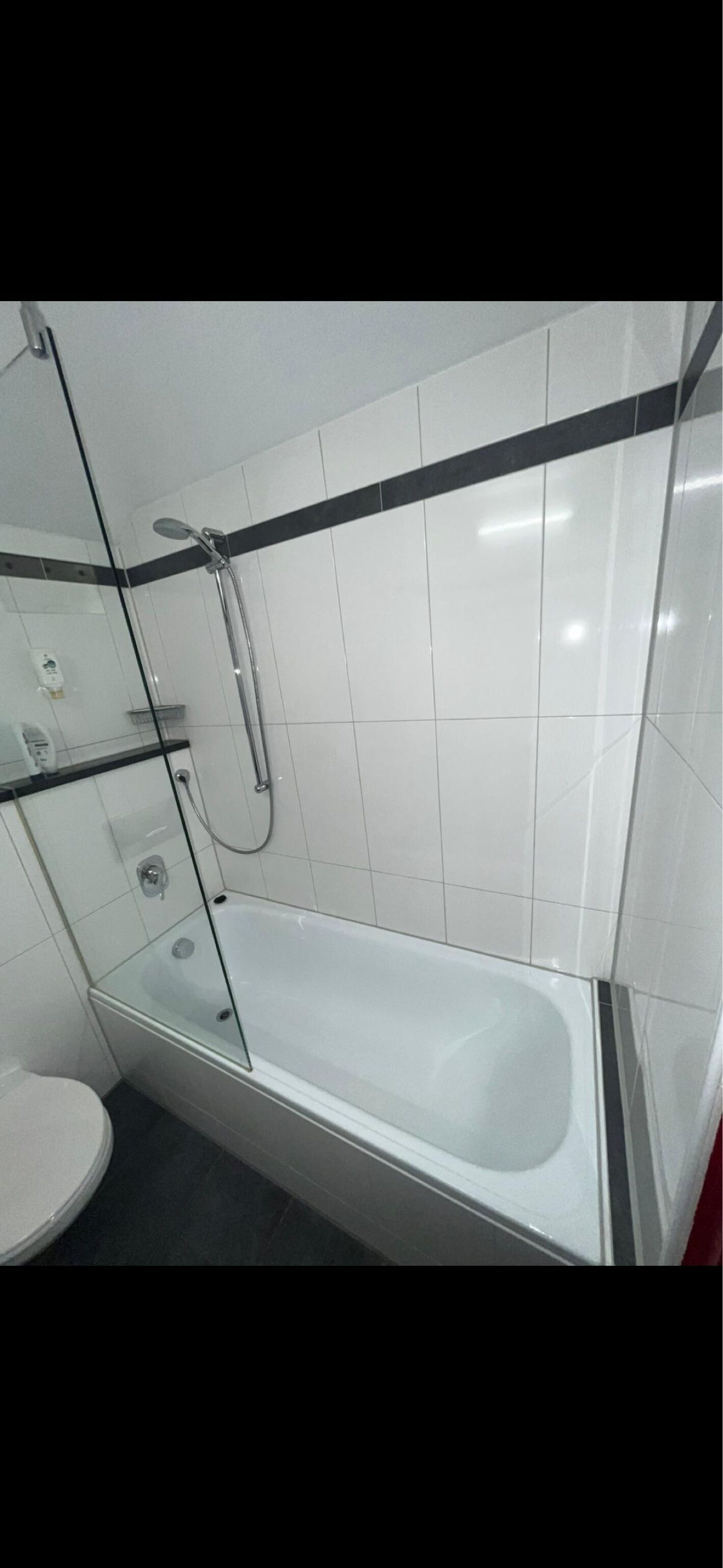 Un bagno con doccia vetrata, vasca da bagno bianca e servizi igienici.