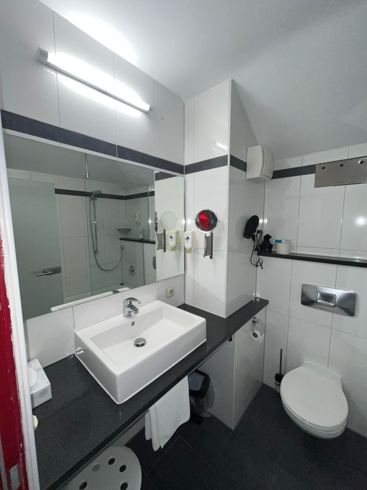 A modern bathroom with a white sink, mirror, and toilet.