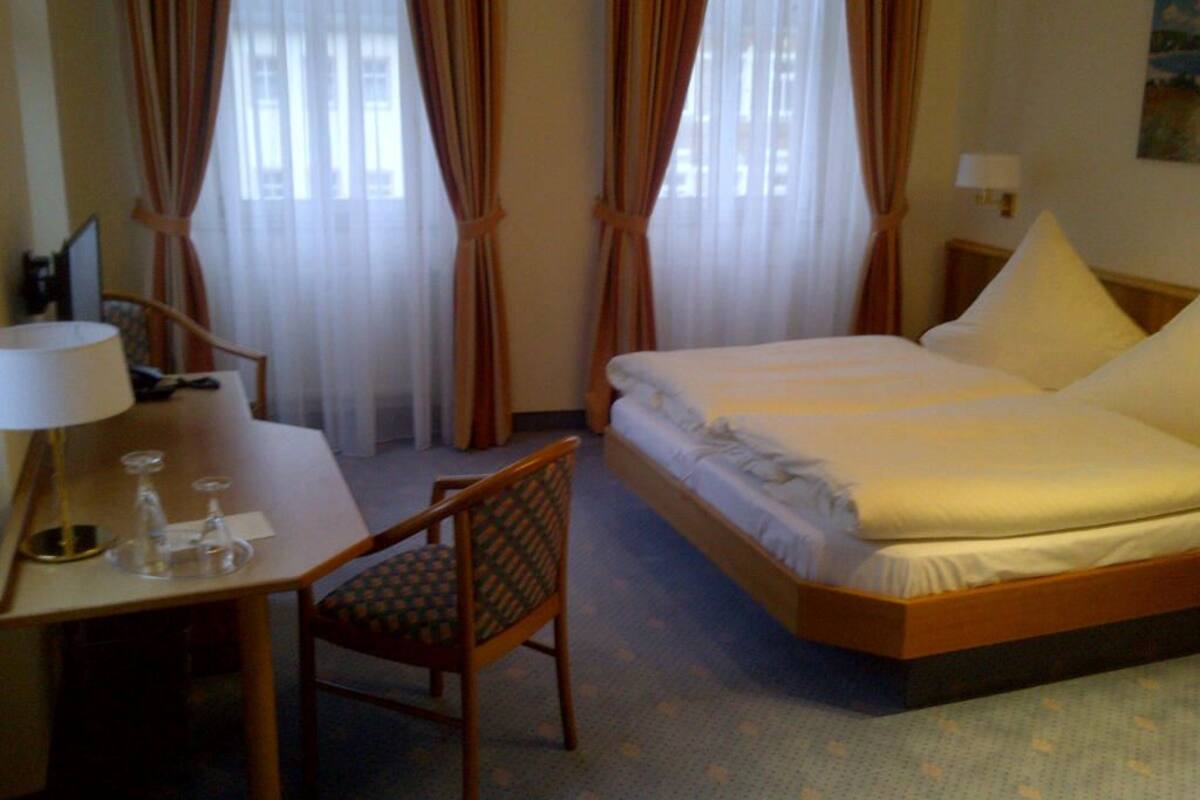 Una habitación de hotel con una cama, un escritorio con lámpara y una silla.