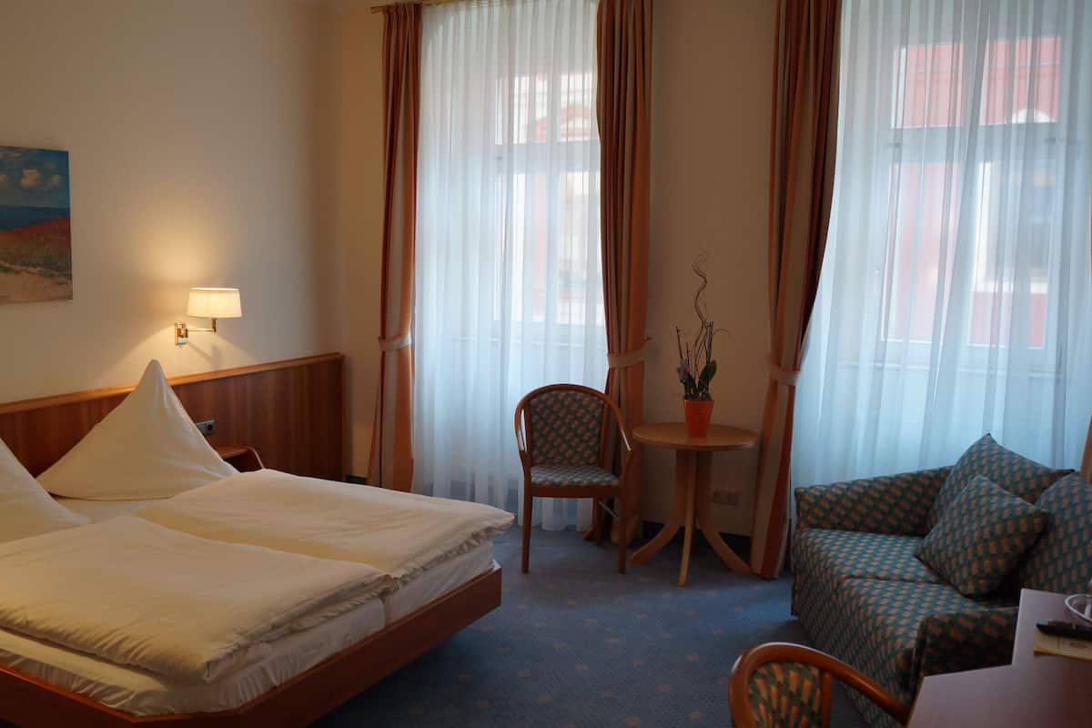 Una habitación de hotel con una cama, una silla, una mesita y un sofá.