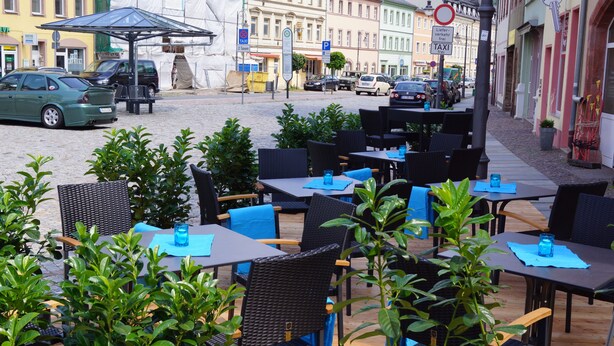 An outdoor cafe with tables and chairs, surrounded by greenery. - Hotel Goldener Löwe (Waldheim)