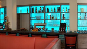 A bar area with a stone wall, red seating, and a blue-lit shelving unit displaying various bottles and glasses. - Hotel Goldener Löwe (Waldheim)