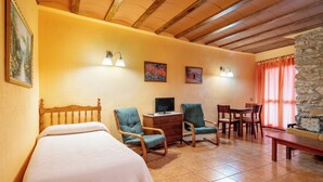 Un dormitorio con una cama, dos sillas, un escritorio y una pared de piedra.