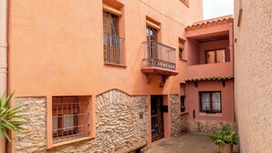 Un callejón estrecho con un edificio de paredes de piedra y fachada rosa.