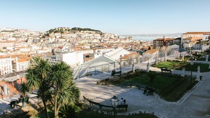 A panoramic view of a cityscape with a prominent white building with a dome, palm trees, and a clear sky. - Bairro Alto Suites (Lisbon)