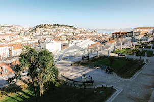 Vista panorámica de un paisaje urbano con un edificio blanco destacado con cúpula, palmeras y cielo despejado.