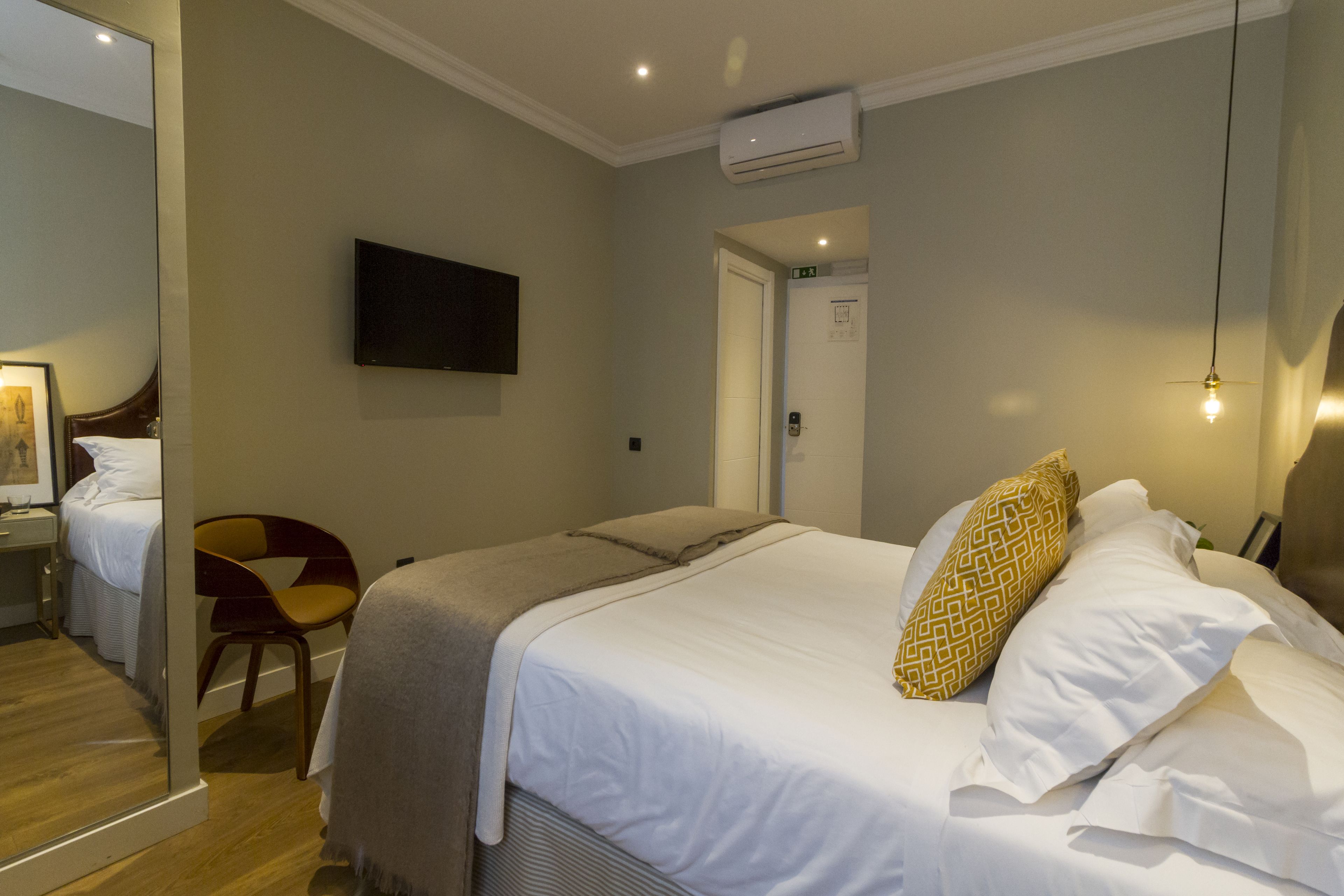 Ein Hotelzimmer mit einem Bett, einem Sessel, einem Fernseher und einer Tür.
