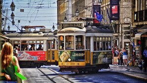 A tram with a Carris logo and a Jameson advertisement, passing through a busy street with pedestrians and shops. - Bairro Alto Suites (Lisbon)