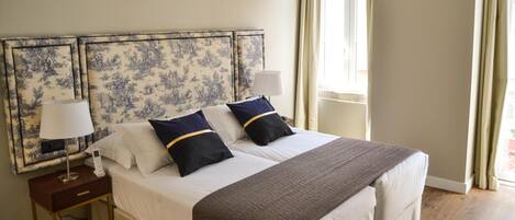 A neatly made bed with a white and brown striped blanket, two navy pillows with gold stripes, and a matching headboard.