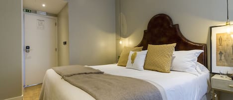 Una habitación de hotel con una cama grande, una mesita de noche y un cuadro enmarcado en la pared.