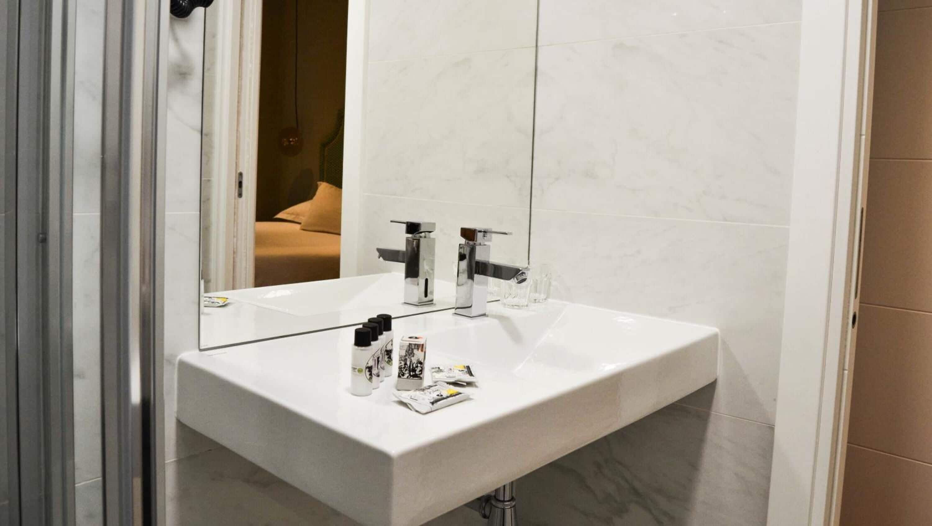 Une salle de bain avec un lavabo blanc, deux robinets et un miroir.