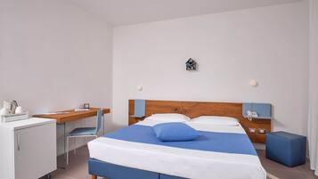 A hotel room with a bed, a desk, a chair, a small table, and a cabinet.