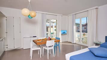 Une chambre d’hôtel moderne avec un balcon, un coin repas et un lit avec une literie bleue.