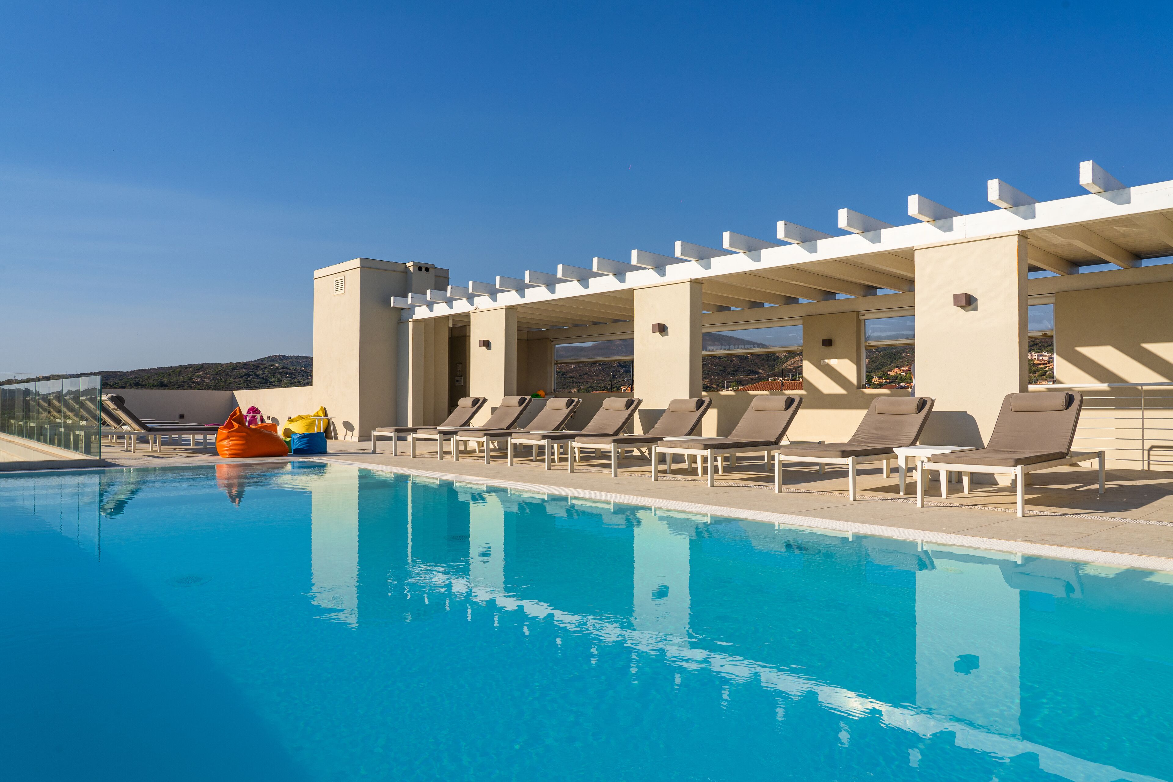 Una piscina con sillones de descanso y una zona de estar cubierta.