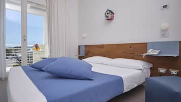 Une chambre d’hôtel avec un lit, une table de chevet, un téléphone, une lampe fixée au mur et une vue sur l’extérieur.