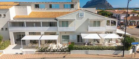 Un hotel con terraza, mobiliario exterior y vistas al mar.