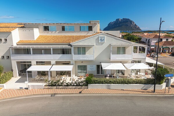 Un hotel con terraza, mobiliario exterior y vistas al mar.