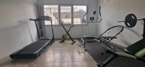A gym with treadmills, a stationary bike, and a weight bench. - Aliter Suites (Santorini)
