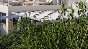 Un resort con zona de piscina, tumbonas y un área de descanso cubierta con sombrillas.