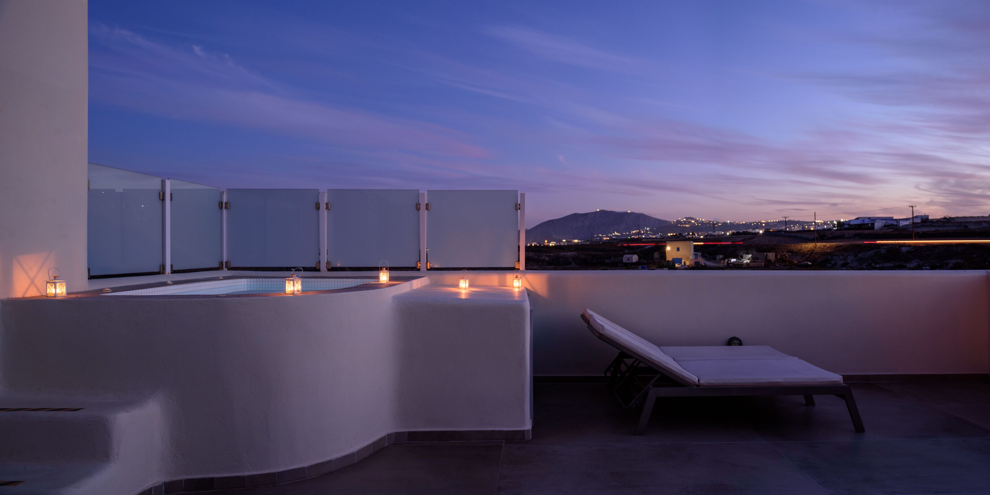 Una terraza en la azotea con piscina, sillones de descanso y velas.