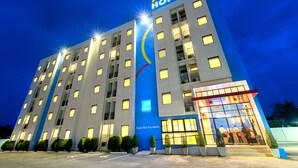 A multi-story hotel with a prominent 'Hop Inn' sign, large windows, and a well-lit entrance. - Hop Inn Chiang Mai (Chiang Mai)
