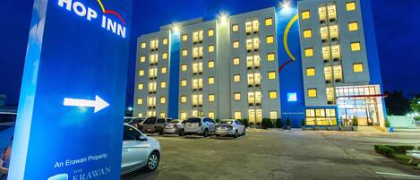 A hotel with multiple floors, a parking lot with several cars, and a prominent sign for the hotel.