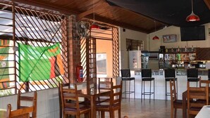 A restaurant with a bar area, wooden chairs, and a tiled floor.