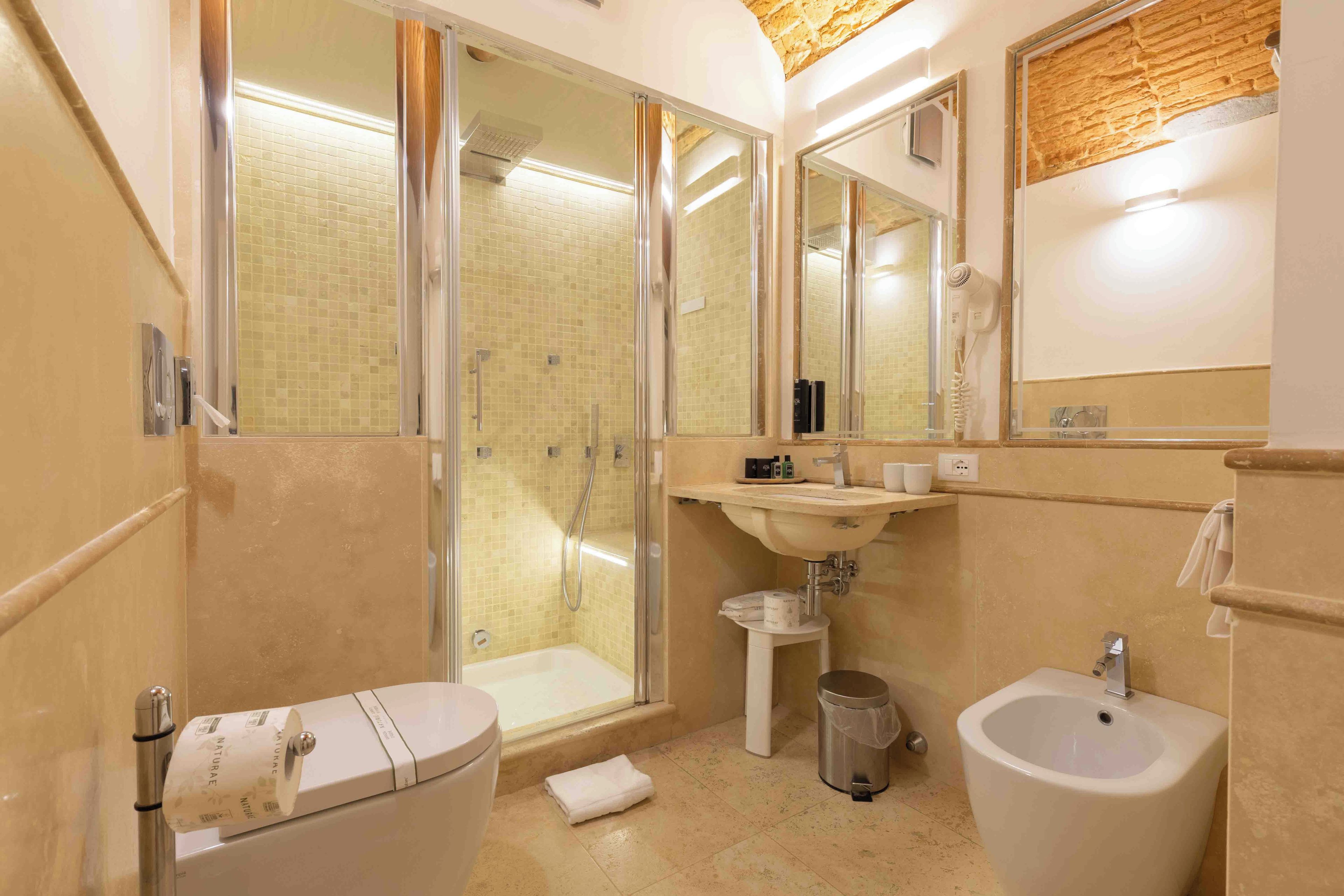 Un bagno con toilette, bidet, lavandino e zona doccia.