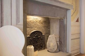 A stone fireplace with a decorative mantel, a woven basket, and a candle holder. - Hotel Renaissance (Florence)