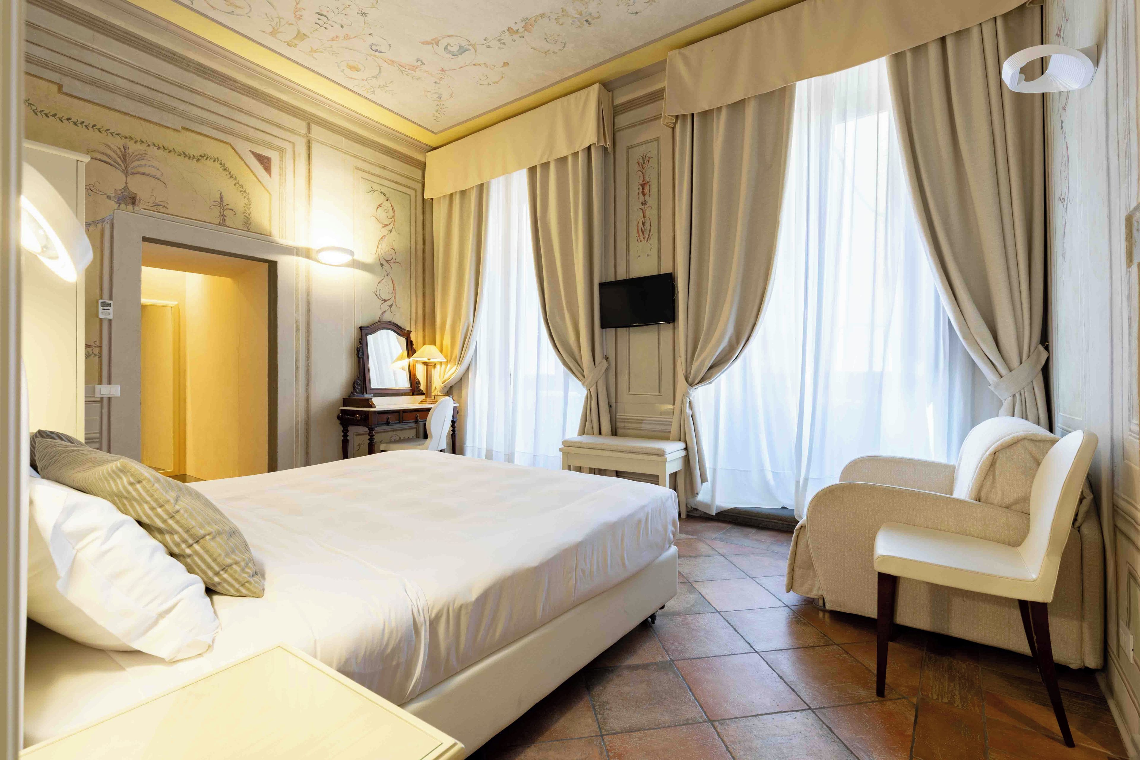 Een hotelkamer met een groot bed, een bureau met lamp, een stoel en een aan de muur bevestigde televisie.