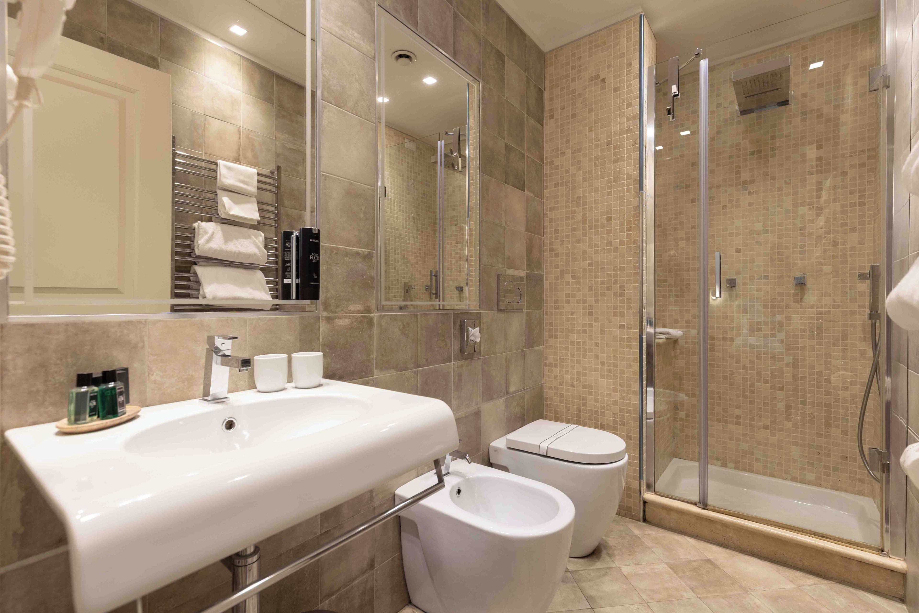 A modern bathroom with a large sink, a toilet, a bidet, and a glass-enclosed shower.
