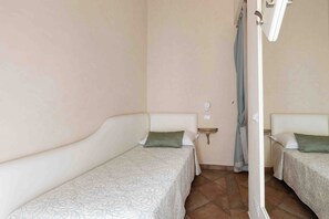 A room with two single beds, each with a pillow and a bedside table. - Hotel Renaissance (Florence)