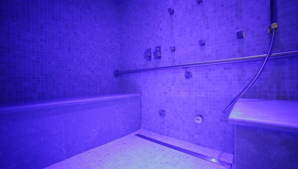 Un baño con pared de azulejos morados, una bañera y una zona de ducha.