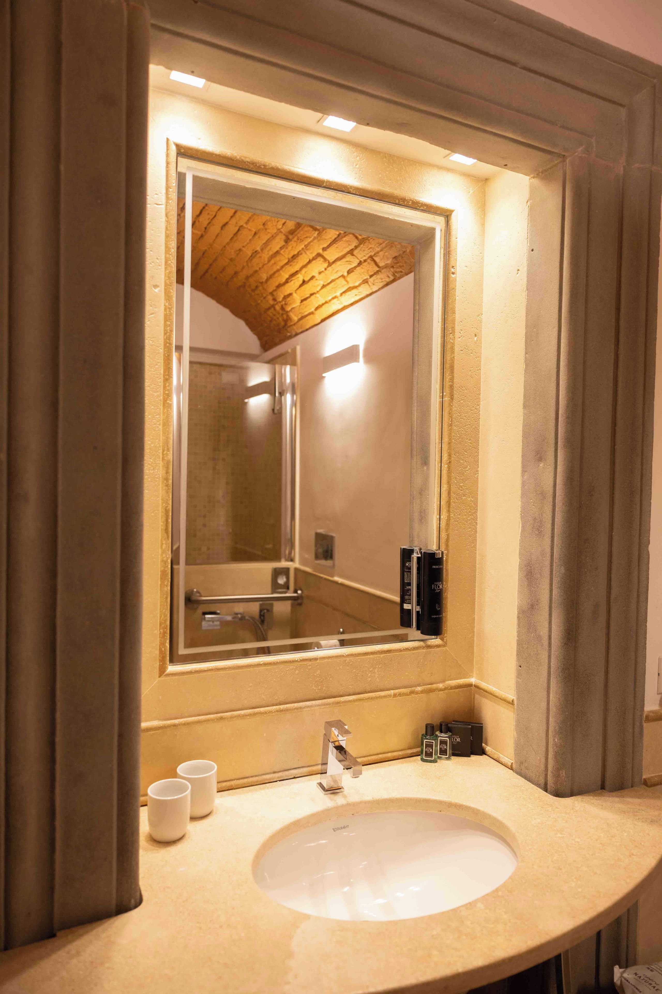 Un baño con un espejo grande, un lavamanos y una ducha.