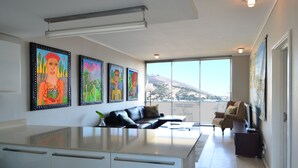 A modern living room with a large window, a sofa, a coffee table, and a TV. - 214 Harbour Bridge (Cape Town)