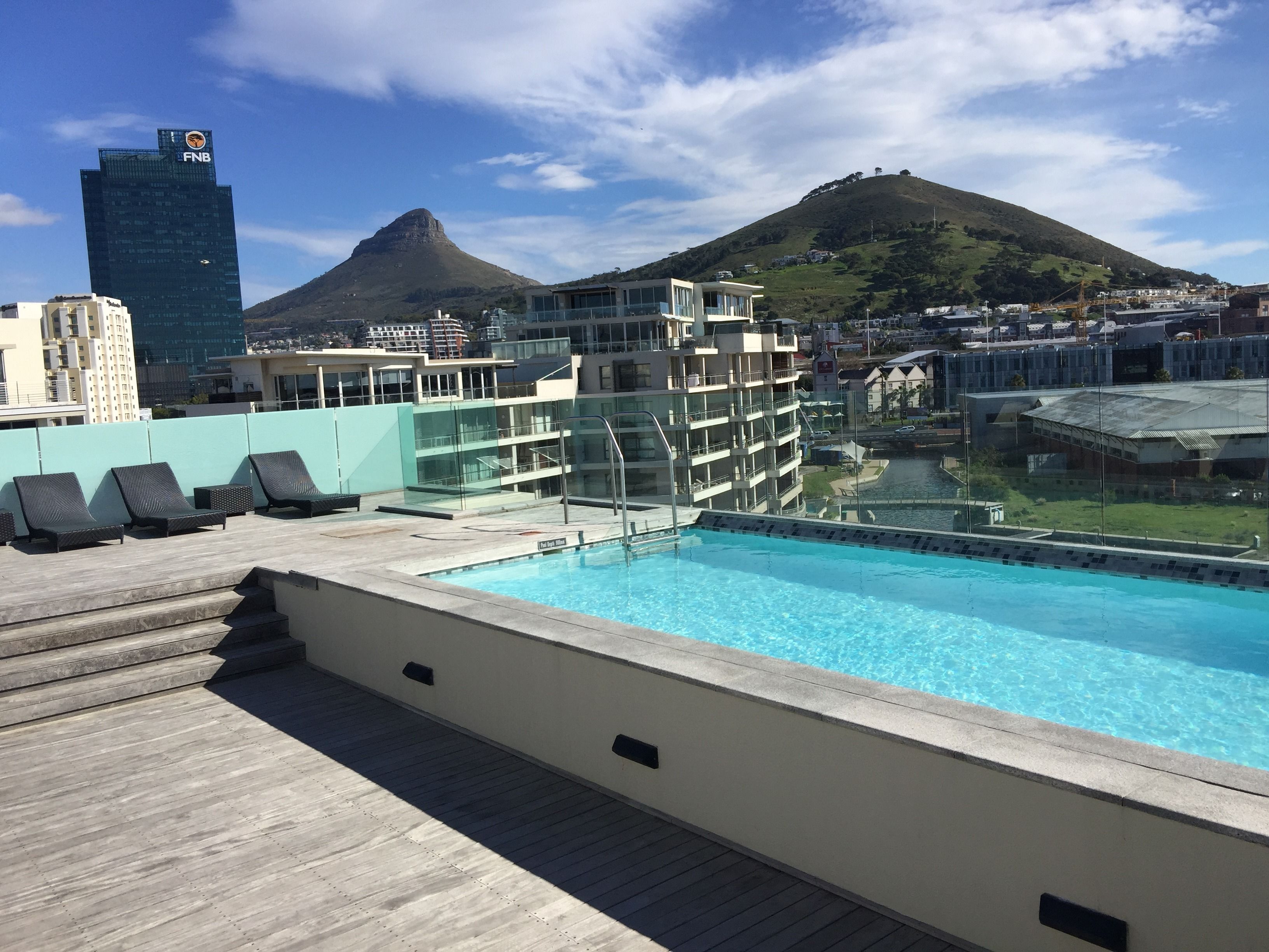 A rooftop pool with a view of a mountain and city buildings.