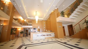 Eine Hotelhalle mit einer Rezeption, einer Treppe und einem Chandelier.