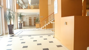 Eine Hotelhalle mit Schachbrettboden, einer Treppe und Topfpflanzen.