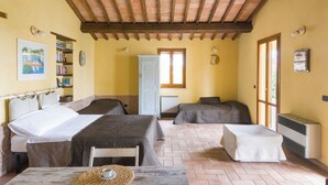 Una habitación con dos camas, una mesa con una taza, una estantería, un radiador y una ventana.
