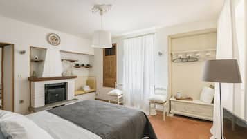 Ein Hotelzimmer mit einem Bett, einem Sessel, einem Schreibtisch, einem Spiegel, einem Kleiderschrank und einem Kamin.