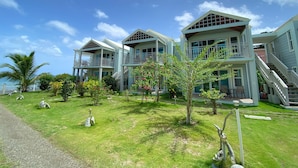A beachfront property with multiple-story buildings, outdoor seating, and a clear view of the ocean. - Ke Villas (West End)