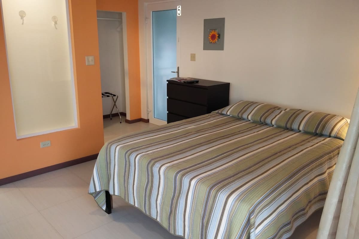 Un dormitorio con cama, cómoda y puerta que da a otra habitación.