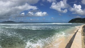 A beach with waves, a clear sky, and distant mountains. - Ke Villas (West End)