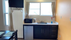 A compact kitchen with a microwave, coffee maker, and sink. - Ke Villas (West End)