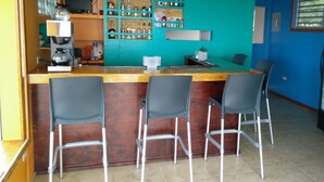 A bar area with a wooden ceiling, a teal-colored wall, and a counter with bar stools. - Ke Villas (West End)