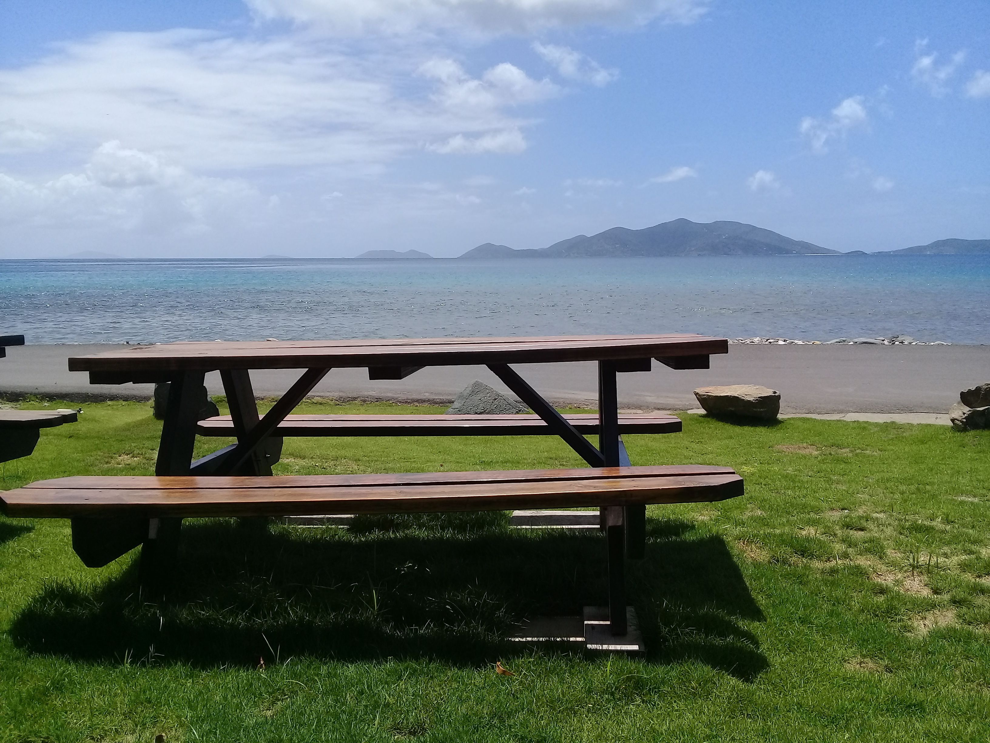 Una mesa de picnic con vistas al mar y montañas al fondo.