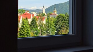Ikkunasta avautuva näkymä kaupunkiin, jossa on rakennuksia ja kirkontorni.
