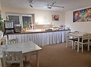 Un café chaleureux avec un coin bar, des places assises et un tableau accroché au mur.
