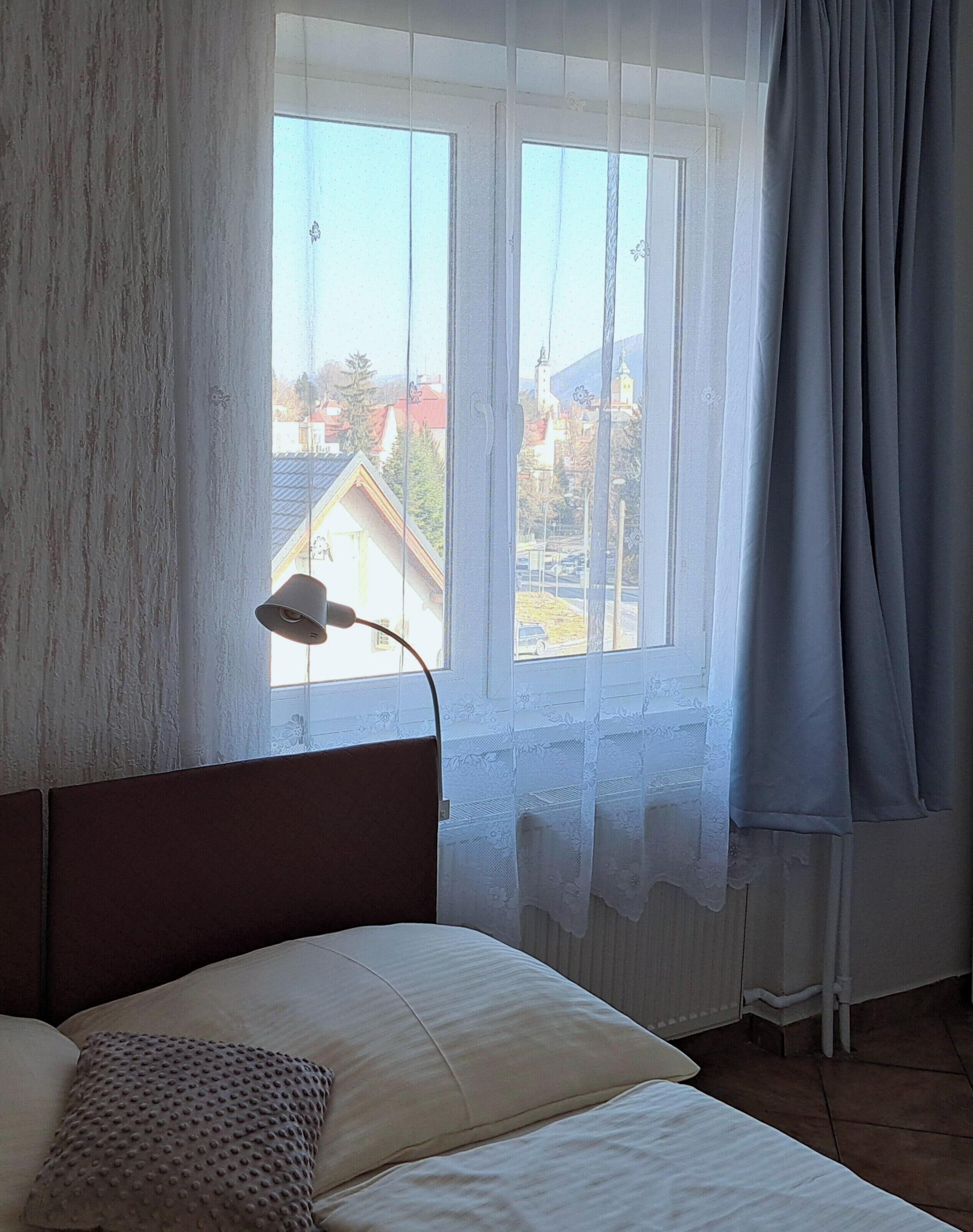 Une pièce avec un lit, une fenêtre avec des rideaux et une lampe.