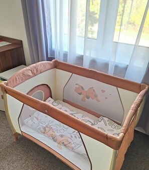 A room with a crib featuring a mesh canopy and patterned bedding. - Penzión Al Corso (Banska Bystrica)
